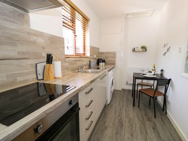 A kitchen with a stove oven sink washing machine small dining table and two chairs at Gilfach Bach in Dolgellau