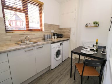 A kitchen with a sink washing machine fridge small dining table with dishes and wine bottle Gilfach Bach Dolgellau