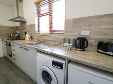 A kitchen with a sink washing machine toaster kettle and canisters on a countertop at Gilfach Bach in Dolgellau