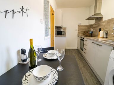 A kitchen with a table set for two with plates bowls wine glasses and a bottle at Gilfach Bach in Dolgellau