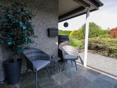 An outdoor patio with two chairs a small table a potted plant a mailbox and a hanging plant ball at Gilfach Bach in Dolgellau