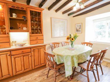 A dining room with a wooden table and chairs a cabinet and a window at Ty Glan Yr Afon in Bontddu near Dolgellau
