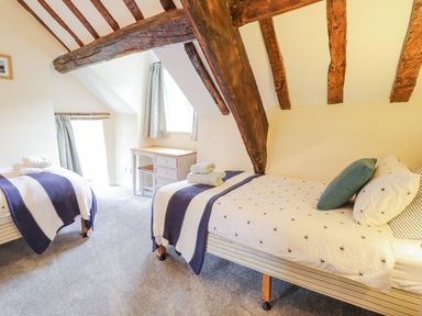 A bedroom with two single beds a small desk under windows and exposed wooden ceiling beams at Ty Glan Yr Afon in Bontddu near Dolgellau