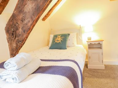 A small bedroom with a single bed a wooden beam a bedside table and a lamp at Ty Glan Yr Afon in Bontddu near Dolgellau