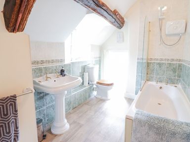 A bathroom with a pedestal sink toilet bathtub and wooden ceiling beam at Ty Glan Yr Afon in Bontddu near Dolgellau