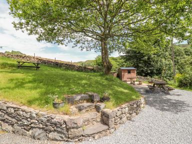 An outdoor area with a tree picnic benches stone steps and a shed at Ty Glan Yr Afon in Bontddu near Dolgellau