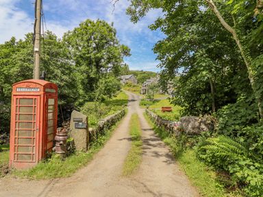 A country lane with a red telephone box and stone houses at Ty Glan Yr Afon in Bontddu near Dolgellau