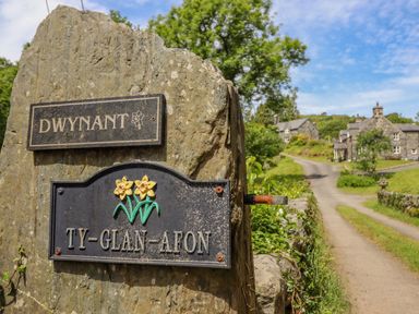 A stone signpost with the names Dwynant and Ty Glan Afon near a country road and stone houses at Ty Glan Yr Afon in Bontddu near Dolgellau