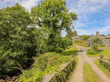 A country road with stone cottages and green trees at Ty Glan Yr Afon in Bontddu near Dolgellau