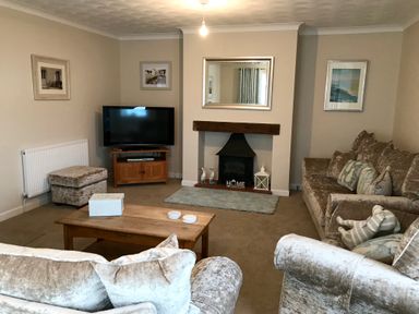 A living room with sofas a coffee table a television and a fireplace at Pen Y Frith Bungalow in Prestatyn