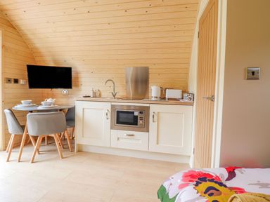 A kitchen area with a microwave sink kettle toaster and a dining table with chairs at Briallen in Bontddu near Dolgellau