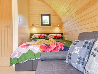 A bedroom with a floral bedspread and a sofa with patterned pillows at Briallen in Bontddu near Dolgellau
