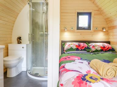 A bedroom with a bed and rolled towels beside a bathroom with a toilet and shower at Briallen in Bontddu near Dolgellau