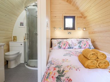 A bedroom with a bed and towels and an adjacent bathroom with a toilet and shower at Eirlys in Bontddu near Dolgellau