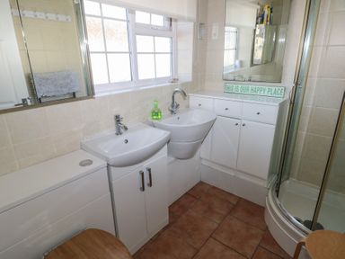 A bathroom with two sinks a corner shower cabinet white cabinets and a window at Kites - 52 Gower Holiday Village in Scurlage near Port Eynon and Rhossili