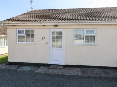 Front view of a single-story building with two windows and a door in the center at Kites - 52 Gower Holiday Village in Scurlage near Port Eynon and Rhossili