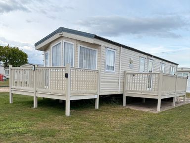 A mobile home with a deck and steps at Caravan 607 in Clacton-On-Sea