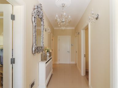A hallway with a silver decorative mirror above a white radiator cover and a chandelier at Killelton Cottage in Camp County Kerry