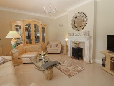 A living room with a glass coffee table a beige sofa a cabinet and a fireplace at Killelton Cottage Camp County Kerry