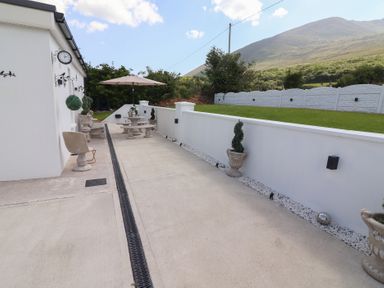 An outdoor patio area with stone tables and benches umbrellas and potted plants at Killelton Cottage in Camp County Kerry