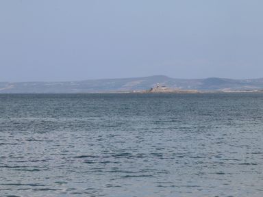 A body of water with a small island and lighthouse in the distance with hills in the background at Killelton Cottage Camp County Kerry