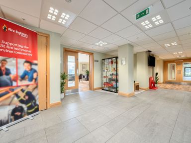 A lobby with a display case and banner at Fire Fighters Charity in an indoor space