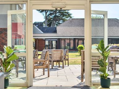 An outdoor patio with wooden furniture and plants at Marine Court First-floor Double Bedroom with Bathroom Littlehampton