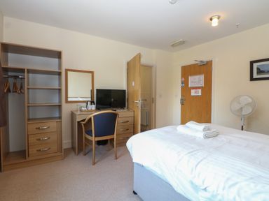 A bedroom with a bed, desk, and television at Bedroom 9 in Littlehampton