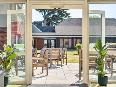 A patio area with wooden chairs and table at Marine Court First Floor Double with Shower Room Littlehampton