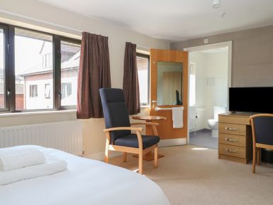 A bedroom with a bed, armchair and TV at Sunset Quarters at Marine Court, Littlehampton