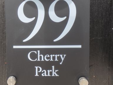 A black house number sign with the number 99 and the text Cherry Park at 99 Cherry Park in Chapel St Leonards