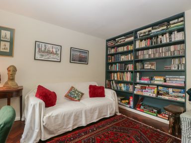 A living room with a sofa and bookshelf at St. Marys House in Church Westcote near Bledington