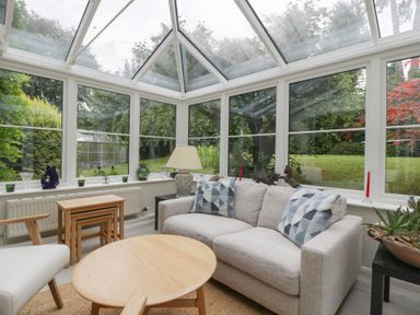A conservatory with seating and tables at St. Marys House Church Westcote near Bledington