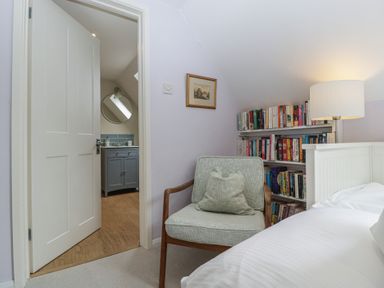 A bedroom with a chair and a doorway to a bathroom at St. Marys House Church Westcote near Bledington
