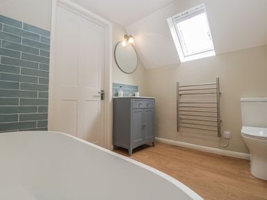 A bathroom with a bathtub and a grey cabinet at St. Marys House Church Westcote near Bledington