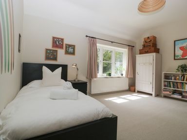 A bedroom with a bed, bookshelf, and window at St. Marys House Church Westcote near Bledington