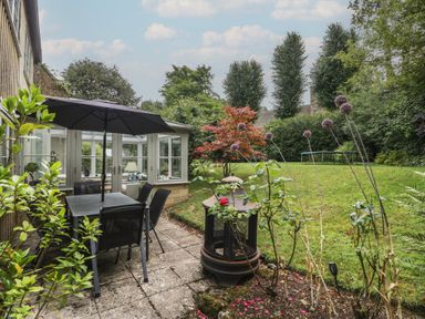 A garden with a table and chairs under an umbrella at St. Marys House Church Westcote near Bledington