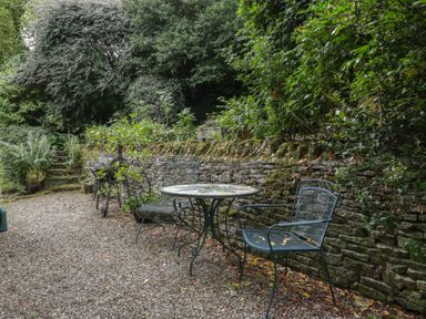 A garden with a table and chairs near a stone wall at St. Marys House Church Westcote near Bledington
