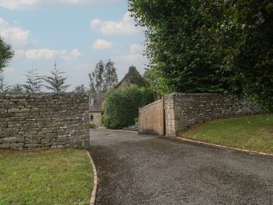 A gate and stone wall with a driveway at St. Marys House Church Westcote near Bledington