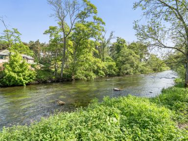 A river with trees and grass beside a house in Penrith