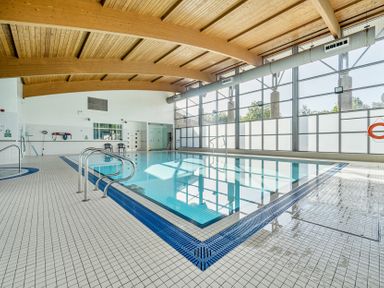 An indoor swimming pool with tiled floor and large windows at Jubilee First-floor Double Bedroom in Penrith