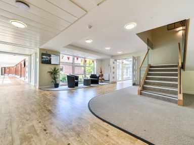 A lobby with a staircase, chairs, table, and potted plant at Jubilee First-floor Double Bedroom Penrith