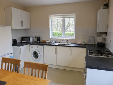 A kitchen with appliances and a dining table at Bungalow 15 Eamont Park in Penrith