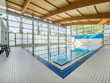 An indoor pool area with deck chairs and large windows at Jubilee Ground-floor Double Bedroom Penrith