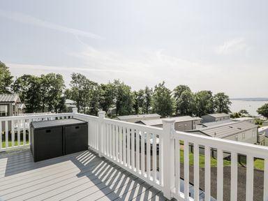 A deck with an outdoor storage container and a view of mobile homes at Number 42 in Wemyss Bay