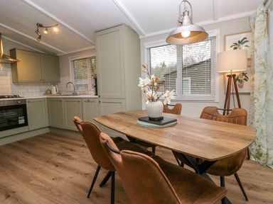 A kitchen and dining area with wooden table and brown chairs at Robins Lodge White Cross Bay near Troutbeck Bridge