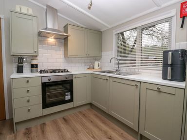 A kitchen with cabinets stove oven sink window and countertop appliances at Robins Lodge White Cross Bay near Troutbeck Bridge