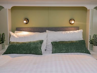 A bedroom with a bed with white and green pillows and built in wall lighting at Robins Lodge in White Cross Bay near Troutbeck Bridge