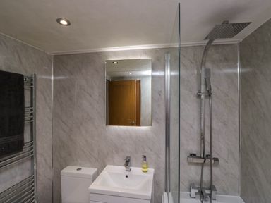 A bathroom with a toilet sink mirror shower and towel rail at Robins Lodge in White Cross Bay near Troutbeck Bridge