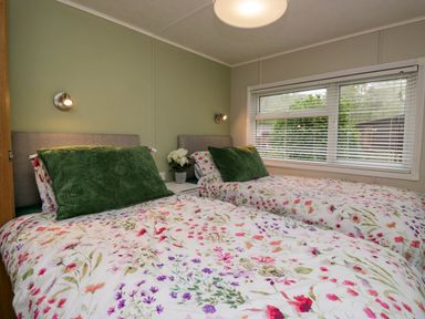 A bedroom with two single beds with floral bedding and green pillows at Robins Lodge White Cross Bay near Troutbeck Bridge